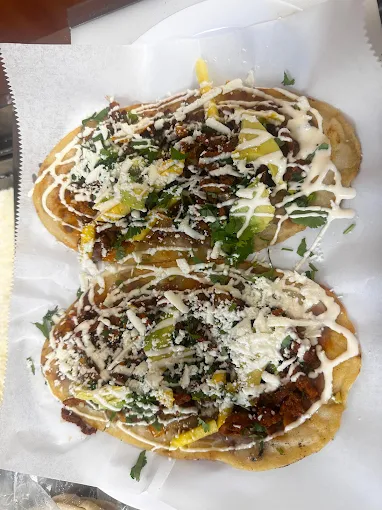 Two huaraches loaded with crema, queso fresco and salsa