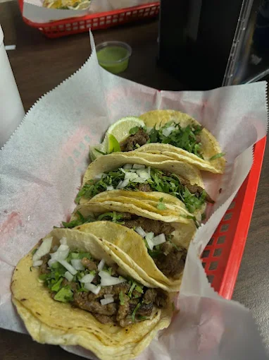 Three street tacos with onion, cilantro and lime